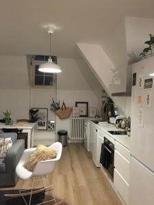 una cocina con armarios blancos y una silla blanca en les chambres de pauline appartements, en Albertville