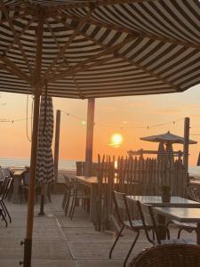 a patio with tables and chairs and a sunset at Appartement 't Zomerhuis in Zandvoort