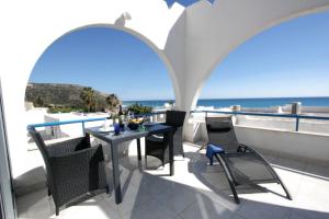 a balcony with a table and chairs and the ocean at Pissouri Beach Apartments in Pissouri