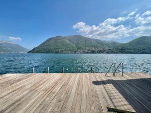 a wooden dock on a lake with mountains in the background at LG LAKE - Boutique apartments and rooms - in Brienno