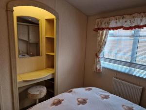 1 dormitorio con cama, espejo y ventana en Castlewigg holiday park Whithorn 2 bed caravan en Newton Stewart