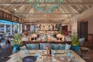 a dining room with a blue couch and tables at Le Barthélemy Hotel & Spa in Gustavia