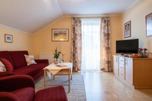 ein Wohnzimmer mit einem roten Sofa und einem TV in der Unterkunft Franzl's Ferienwohnungen in Bad Birnbach