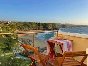 a table and chairs on a balcony with a view of the ocean at Apartamento Sunset con vistas Playa de Los Locos in Suances