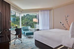 فندق جيه دوبل يو ماريوت هونغ كونغ في هونغ كونغ: غرفه فندقيه بسرير وكرسي ونافذه