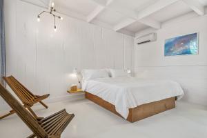 1 dormitorio blanco con 1 cama y 1 silla en Ruschmeyers Hotel, en Montauk