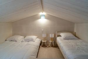 dwa łóżka w sypialni z lampką na ścianie w obiekcie A moins de 500m de la plage vacances a L Epine w mieście LʼÉpine