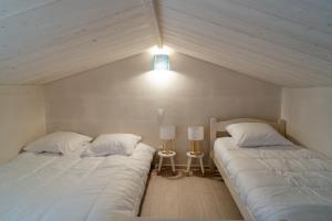 two beds in a bedroom with a light on the wall at À moins de 500m de la plage, 2 adultes - 3 enfants in LʼÉpine