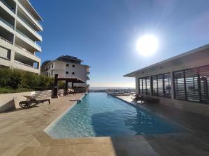 une piscine en face d'un bâtiment dans l'établissement Charmant F2 à SkyNui, piscine de 25m et vue mer, à Papeete