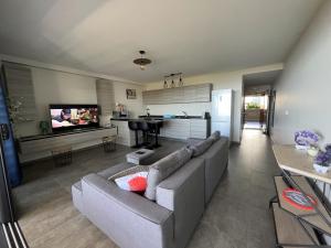 uma ampla sala de estar com um sofá e uma cozinha em Charmant F2 à SkyNui, piscine de 25m et vue mer em Papeete