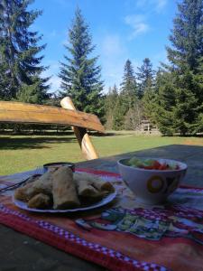 una mesa con un plato de comida y un bol de fruta en Kućica za odmor '' Idila '' en Mitrovac