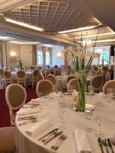 een eetkamer met witte tafels en stoelen en een vaas met bloemen bij Hotel Radmilovac in Belgrado