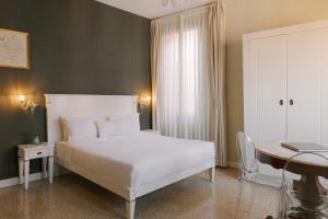 una camera con letto bianco e scrivania di Salute Palace powered by Sonder a Venezia