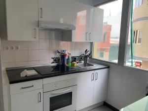 a kitchen with white cabinets and a sink and a window at Las Canteras 128 in Las Palmas de Gran Canaria