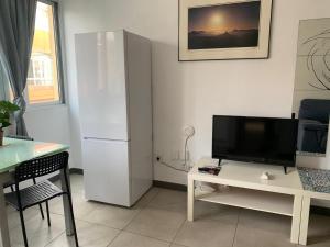 a living room with a white refrigerator and a table at Las Canteras 128 in Las Palmas de Gran Canaria