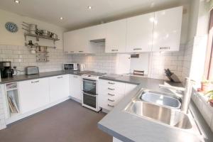 a kitchen with white cabinets and a stainless steel sink at Beck Yeat Cottage Coniston in Coniston