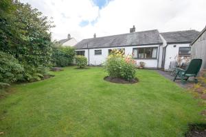 a backyard of a house with a lawn and a house at Beck Yeat Cottage Coniston in Coniston
