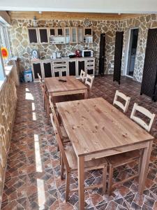a patio with wooden tables and chairs and a kitchen at Pensiunea Blue House in Vadu