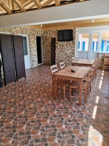 a dining room with two tables and a tv on a stone wall at Pensiunea Blue House in Vadu
