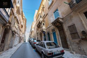 a white car parked on a street between buildings at 1BR Charming townhouse in capital city with WIFI by 360 Estates in Valletta