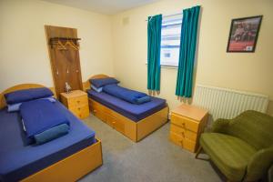 Kirkwall Youth Hostel في كيركوول: غرفة نوم بسريرين وكرسي ونافذة