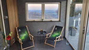 Duas cadeiras e uma mesa num alpendre com uma janela em Apartma Lara em Lesično