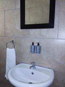 lavabo blanco en el baño con espejo en Ditsaleng Bed and Breakfast, en Vanderbijlpark