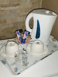 - Hervidor de té y tazas en bandeja blanca en Ditsaleng Bed and Breakfast, en Vanderbijlpark