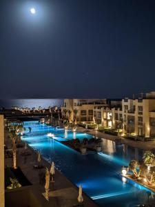 una piscina por la noche con la luna en el fondo en Mangroovy - 1BR GF +2 wall beds Garden & Pool view, en Hurghada