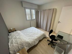 1 dormitorio con cama, escritorio y ordenador en Urban flat au cœur de Lorient, en Lorient