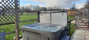 une baignoire posée à côté d'une clôture dans l'établissement Blashford Manor Farmhouse Holiday Cottage - The Shire Cottage, à Ellingham 5 autres photos