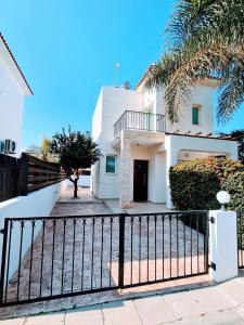 a white house with a gate and a palm tree at Villa Alkioni 31 in Paralimni