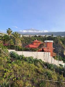 un edificio rosso in cima a una collina con palme di Playa San Marcos Apt.Mirador del Roque a Icod de los Vinos