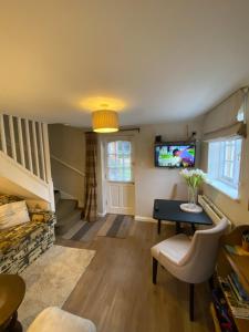 a living room with a table and a tv at Charming 1 Bedroom Cottage Style Maisonette by HP Accommodation in Milton Keynes