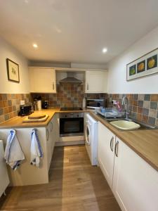 a kitchen with a sink and a stove top oven at Charming 1 Bedroom Cottage Style Maisonette by HP Accommodation in Milton Keynes
