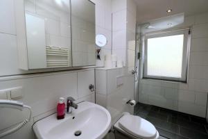 a bathroom with a sink and a toilet and a mirror at Aparthotel Kompass A 102-103 in Essen