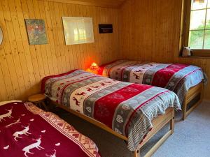 two beds in a room with wooden walls at Résidence « la Forêt » in Les Mosses