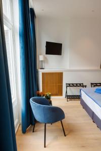 a bedroom with a blue chair and a bed at APL8 St-Anna B&B in Bruges