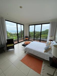 um quarto com uma cama grande e janelas grandes em Vista Lapas Nativa Resort em Jacó