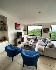 a living room with a couch and two blue chairs at Vista Lapas Nativa Resort in Jacó