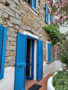 een stenen huis met blauwe deuren en bloemen bij Villa TERRA in Oliena