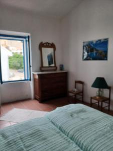 een slaapkamer met een bed, een spiegel en een raam bij Villa TERRA in Oliena