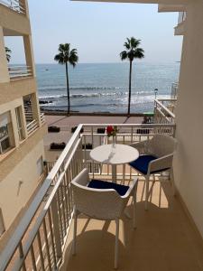 een balkon met een tafel en stoelen en het strand bij Apartamentos Alborada in Cala Millor