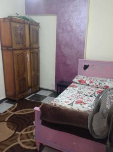 a bedroom with a bed and a wooden cabinet at خالد بن الوليد بجوار كشرى التحرير in Alexandria