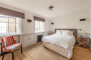 a bedroom with a bed and a chair and windows at Stunning 3 Bed Townhouse in the heart of Mayfair in London