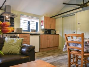 a living room with a couch and a kitchen at Hideaway at Coomb Bank Farm in Axminster