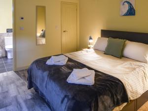 a bedroom with a large bed with towels on it at Hideaway at Coomb Bank Farm in Axminster