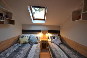 two beds in a small room with a window at Słoneczne Apartamenty w Poddąbiu in Poddąbie