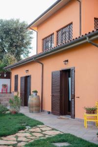 an orange house with brown doors and a yellow bench at Agriturismo I Grappoli in Alberese