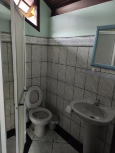 a bathroom with a toilet and a sink at Cabelera's House in Bombinhas